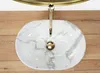 A top-down view of a marble-patterned sink with a gold faucet. Náhled obrázku produktu