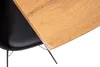 A close-up view of a table with a wooden top and black legs, partially obscuring a black chair. Produktbild-Vorschau