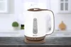 A white and brown electric kettle sits on a dark wooden surface in a kitchen setting. Náhľad obrázku produktu
