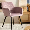 A pink velvet chair with black legs is shown in a room with a wooden cabinet and a mirror in the background. Produktbild-Vorschau