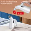 A split image showing a hand holding a garment steamer and a close-up of a garment steamer on a table with folded clothes. Podgląd zdjęcia produktu