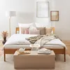 A bedroom scene with a bed, pillows, blankets, and a storage bench. Anteprima dell’immagine prodotto