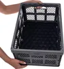 Hands holding a gray collapsible storage crate with a black interior. Produktbild-Vorschau