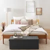 A bedroom scene featuring a bed with pillows and blankets, a floor lamp, and a storage bench in the foreground. Náhled obrázku produktu