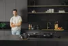 A man stands in a modern kitchen with cookware on the counter. Produktbild-Vorschau