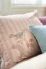 A close-up of pillows on a bed, with one pillow featuring a bird embroidery. Produktbild-Vorschau
