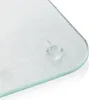 A close-up view of the corner of a clear glass cutting board with a textured surface and rounded edges. Anti-slip pads are visible on the underside of the corner. Produktbild-Vorschau