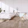 A bedroom scene with a bed and a drying rack with a towel. Podgląd zdjęcia produktu