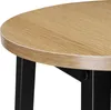A close-up view of the edge of a round wooden tabletop with black metal legs. Náhled obrázku produktu