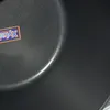 A close-up view of the inside of a black cooking pot with a label. Produktbild-Vorschau