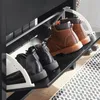 A close-up view of a black shoe cabinet with two open drawers, displaying several pairs of boots and shoes. Náhľad obrázku produktu