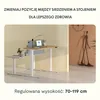 A modern, adjustable desk with a laptop and accessories, set against a clean, neutral background. A stylized human sculpture is visible in the background on the right. Podgląd zdjęcia produktu