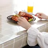 A person is eating a meal at a table covered with a transparent tablecloth. Náhled obrázku produktu