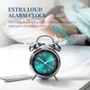 A person sleeping in bed with an alarm clock in the foreground. Voir les images du produit