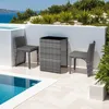 A rattan furniture set with two chairs and a table is placed on a patio next to a swimming pool, with a view of the sea and vegetation in the background. Voir les images du produit