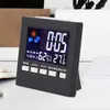 A digital alarm clock with a black frame is displayed on a white surface, with a blurred background. Produktbild-Vorschau