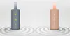Two cylindrical Bluetooth speakers are displayed on a sand-like surface with concentric circle patterns. Anteprima dell’immagine prodotto