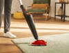 A person is using a steam mop on a rug in a living room. Produktbild-Vorschau