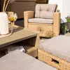 A close-up view of outdoor rattan furniture, including a chair, table, and ottoman, with drinks on the table. Produktbild-Vorschau