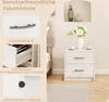 A bedside table with two drawers is shown next to a bed, with decorative items on top and in a wall niche. Podgląd zdjęcia produktu