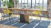 A dining table and chairs set in a bright, modern room with large windows. Produktbild-Vorschau