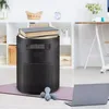 Schwarzer Stoff-Aufbewahrungsbehälter mit Griffen und einer Vordertasche, der zwei Bücher hält, auf einer Yogamatte neben Hanteln und einem Laptop Produktbild-Vorschau