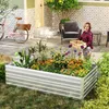 A woman is gardening in a raised metal planter filled with flowers and plants. A pink bicycle is parked nearby. Voir les images du produit