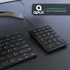 A black wired numpad and a portion of a keyboard are shown on a dark surface, with a monitor stand in the background. Voir les images du produit