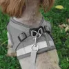 A close-up of a dog wearing a gray harness with reflective strips, outdoors on grass. Náhled obrázku produktu