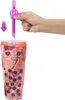 A hand is inserting a pink straw into a clear plastic cup filled with a pink, bobble-like toy. Podgląd zdjęcia produktu