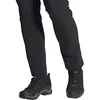 Close-up of a person's legs wearing black hiking pants and black hiking boots. Náhled obrázku produktu