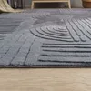 A close-up view of a grey rug with a geometric pattern, placed on a wooden floor. Produktbild-Vorschau