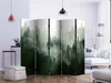 A room divider with a forest scene is placed in a living room setting, next to a sofa and a floor lamp. Produktbild-Vorschau