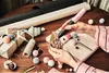 A person is using a pink and black Bosch hot glue gun to decorate a gift box with pom-poms and a tag that says 'Love'. Produktbild-Vorschau