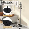 A floor lamp with three conical lampshades is shown in a living room setting next to a sofa. Close-up insets highlight the lamp's base and its non-slip strips. A cat is playfully interacting with the lamp. Produktbild-Vorschau