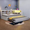 A bedroom scene featuring a white daybed with a pull-out trundle bed, a bookshelf headboard with integrated lighting, and decorative wall art. Produktbild-Vorschau