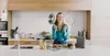 A woman is in a modern kitchen, holding cooking pans. Produktbild-Vorschau