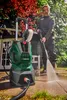 A man is using a pressure washer in a garden setting. Produktbild-Vorschau