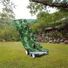 A camouflage-patterned lawnmower cover is draped over a lawnmower in a grassy yard with trees and a stone wall in the background. Produktbild-Vorschau