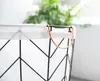 Close-up of the top of a black wire basket with a white fabric liner and copper handles. Produktbild-Vorschau