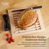 A wooden bread cutting board with a loaf of bread, a knife, a pepper grinder, and cherry tomatoes on a wooden surface. Produktbild-Vorschau