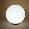 A glowing white sphere sits on a brown surface. Produktbild-Vorschau