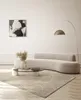 A modern living room with a curved sofa, coffee table, rug, and artwork. Produktbild-Vorschau