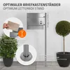 A silver letterbox stand is shown outdoors next to a potted plant and a topiary tree. The image includes text overlays highlighting features and dimensions. Náhled obrázku produktu