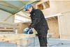 A construction worker is using a power planer on a wooden beam in a building under construction. Anteprima dell’immagine prodotto
