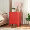 A red nightstand with a lamp and flowers on top, next to a bed. Anteprima dell’immagine prodotto