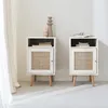 Two white bedside tables with rattan fronts are shown in a room with sheer curtains. Produktbild-Vorschau