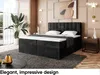 A bedroom scene featuring a black upholstered boxspring bed with a mattress and topper, a large potted plant, and decorative items. Produktbild-Vorschau
