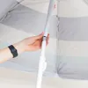A hand adjusting the pole of a striped umbrella. Produktbild-Vorschau