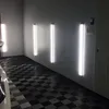 A garage or workshop with checkered flooring and vertical fluorescent lights mounted on the wall. Anteprima dell’immagine prodotto